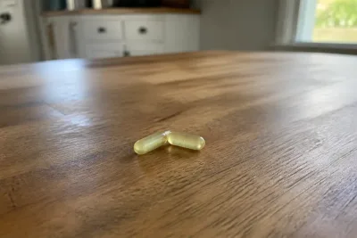 Two pale yellow citrus bergamot capsules resting on a wooden kitchen table